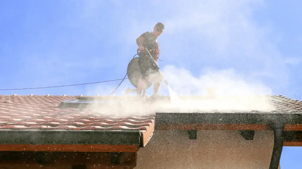 A professional using high-pressure washing on a tiled roof in Australia