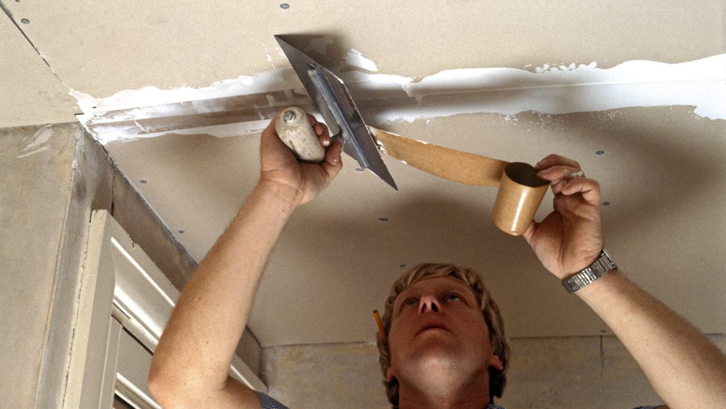 homeowner applying plaster to a patched ceiling